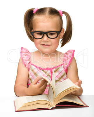 Little girl is flipping over pages of a book