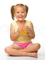 Little girl drinks orange juice