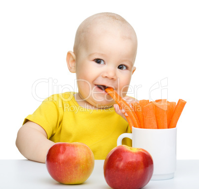 Cute little boy eats carrot and apples