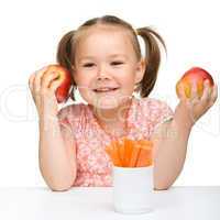 Cute little girl eats carrot and apples