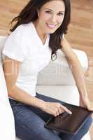 Young Brunette Woman Using Tablet Computer At Home on Sofa