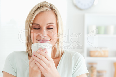 Close up of a woman taking in smell of coffee with her eyes clos