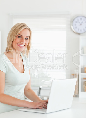 Blonde woman with a laptop looking into the camera