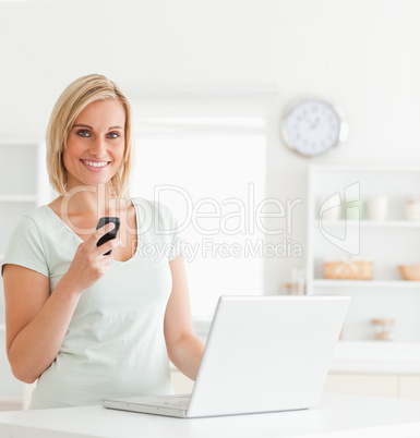 Cute woman with a mobile and a laptop smiling into the camera