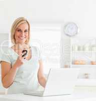 Cute woman with a mobile and a laptop smiling into the camera