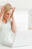 Upset woman looking at her laptop not knowing what to do