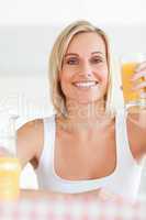 Smiling woman toasting with orange juice