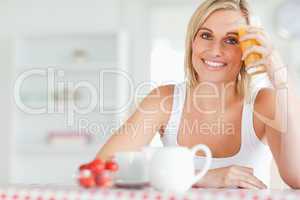 Woman holding glass of orangejuice against her forehead