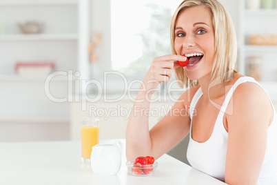 Young woman sitting at table eats strawberries