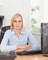 Serious blonde woman sitting behind a desk