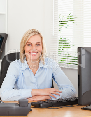 Smiling blonde woman sitting behind a desk