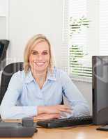 Smiling blonde woman sitting behind a desk