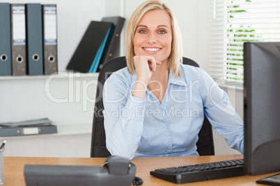 Smiling woman with chin on hand behind a desk