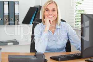 Smiling woman with chin on hand behind a desk
