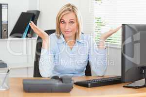 Young blonde woman sitting behind desk not having a clue what to