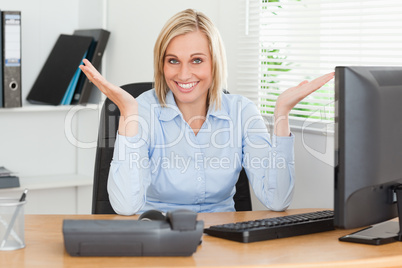 Smiling blonde woman sitting behind desk not having a clue what
