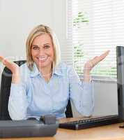 Smiling woman sitting behind desk not having a clue what to do n
