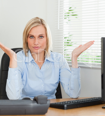 Serious woman sitting behind desk not having a clue what to do n