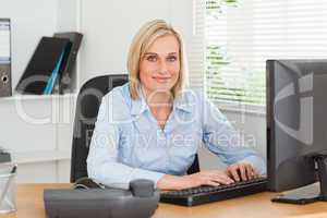 Working woman in front of a screen looks into camera