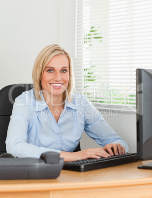 Working blonde woman in front of a screen looks into camera