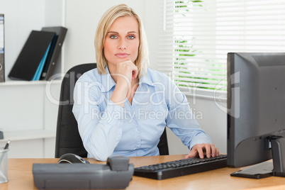 Working serious woman in front of a screen looking into camera