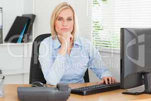 Working serious woman in front of a screen looking into camera