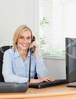 Smiling blonde businesswoman on the phone looking into camera