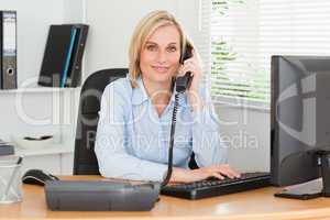 Smiling businesswoman on the phone looking into camera