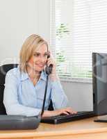 Smiling blonde businesswoman on the phone looking at her screen