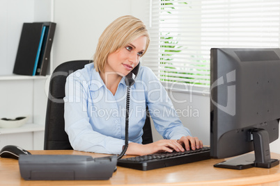 Working businesswoman on the phone while typing