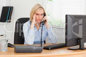 Charming businesswoman on phone while having headache looks into