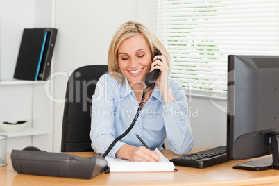 Cute businesswoman on phone writing something down