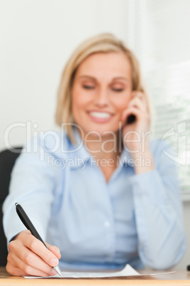 Portrait of a cute businesswoman on mobile noting something with