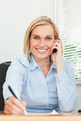 Portrait of a businesswoman looking into camera while noting som