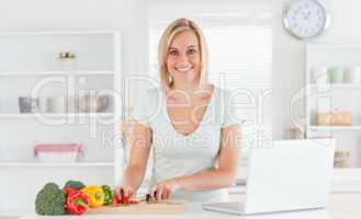 Close up of a young woman looking into camera while cutting pepp