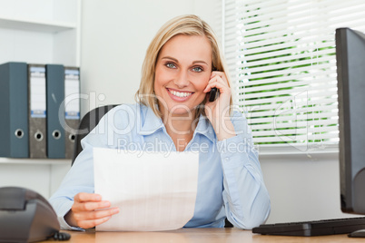 Portrait of a businesswoman looking up from a letter while phoni