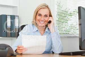 Portrait of a businesswoman looking up from a letter while phoni