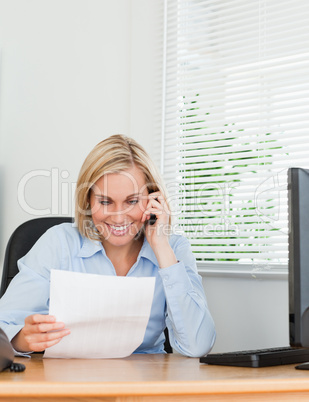 Businesswoman phoning and reeding a paper