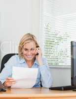 Businesswoman phoning and reeding a paper