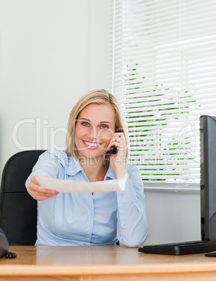 Businesswoman phoning and passing a paper