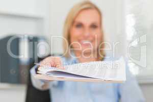 Smiling businesswoman passing a paper looks into camera