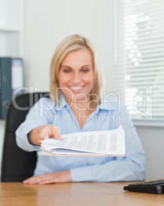 Smiling blonde businesswoman passing a paper looking at it