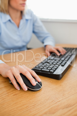 Blonde businesswoman with hands on mouse and keyboard