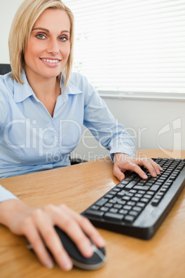 Smiling businesswoman with hands on mouse and keyboard