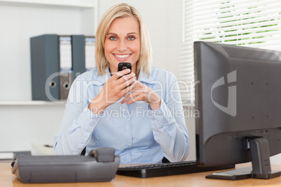 Smiling businesswoman with mobile looking into camera