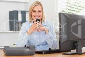 Smiling businesswoman with mobile looking into camera