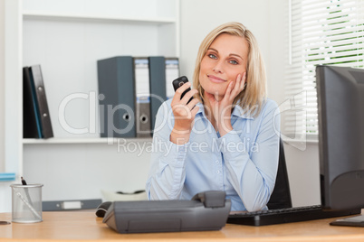 Smiling blondebusinesswoman with mobile looking into camera