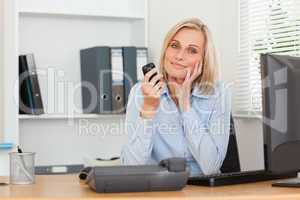 Smiling blondebusinesswoman with mobile looking into camera