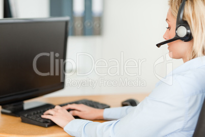 Close up of a blonde businesswoman with headset working with com