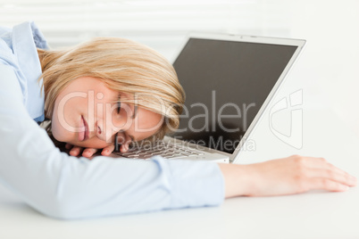 Cute blonde woman sleeping on her notebook holding cup of coffee